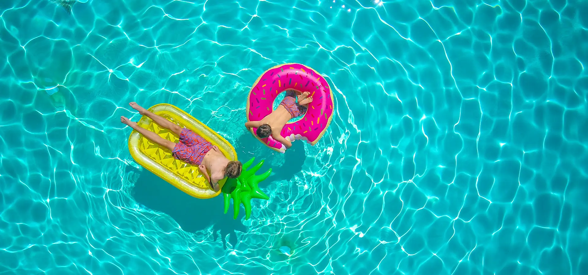 Vogelperspektive von zwei Kindern auf bunten Schwimmhilfen