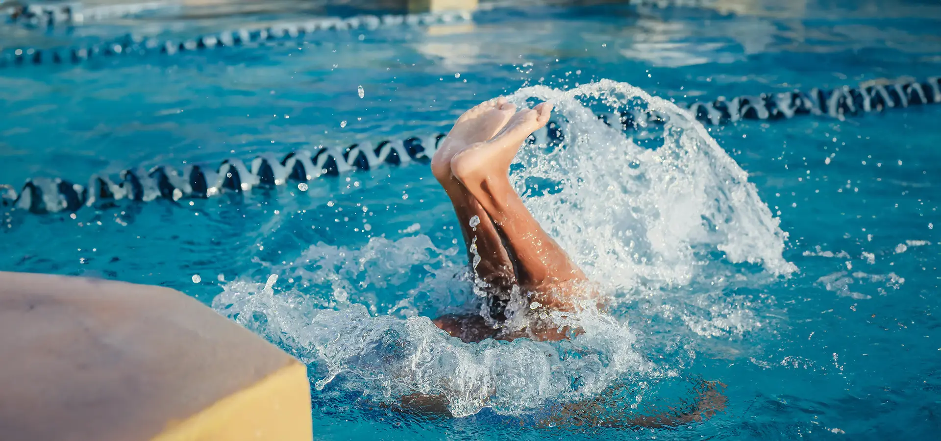 zwei Füße schauen aus dem Wasser und spritzen herum